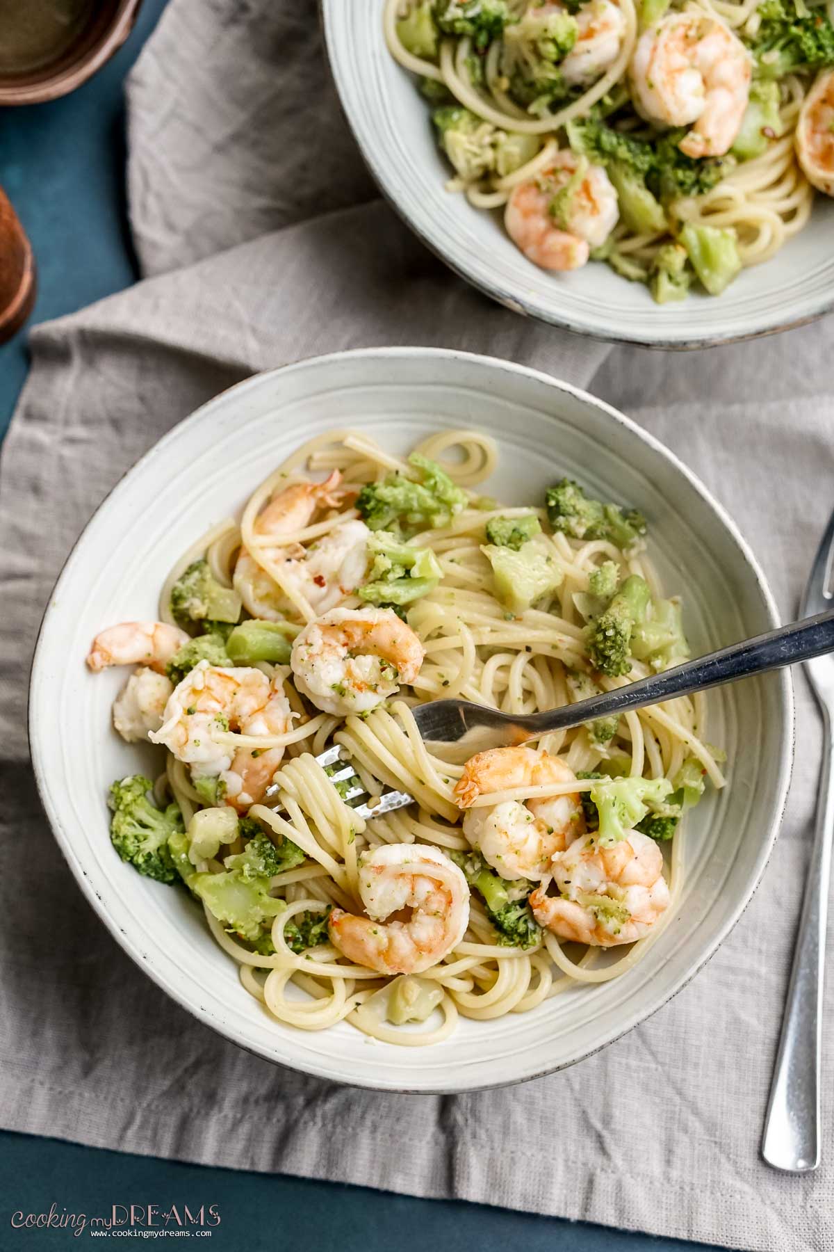 plate of spaghetti with shrimp and broccoli with a fork